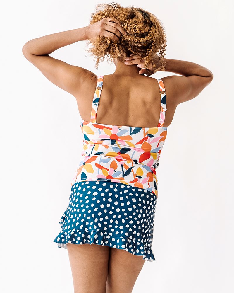 Photo of a woman wearing a June floral square neck swim top and an Indigo dot swim skirt bottom back angle